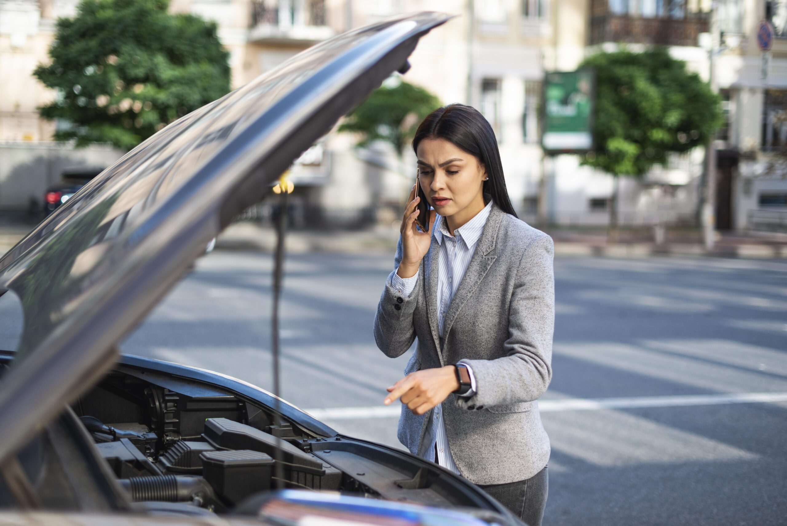 businesswoman talking phone while her car broke down